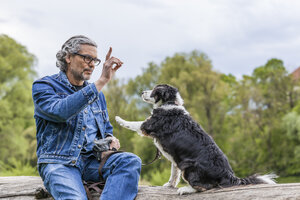 Älterer Mann unterrichtet seinen Hund - TCF05413