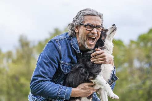 Porträt eines glücklichen älteren Mannes, der seinen Hund knuddelt - TCF05414