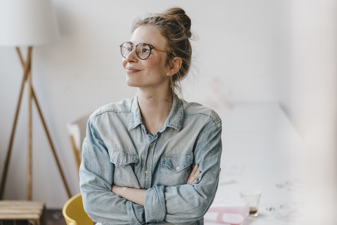 Lächelnde junge Frau im Büro mit Blick zur Seite, lizenzfreies Stockfoto