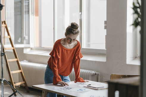 Young woman at table working on script templates - KNSF01489