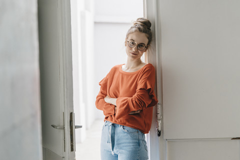 Portrait of young woman leaning against door stock photo