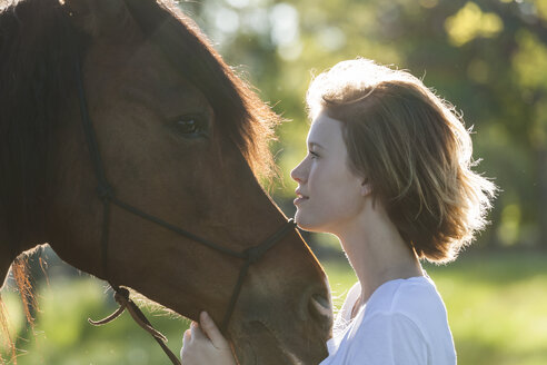 Profile von junger Frau und Pferd im Gegenlicht - TCF05422