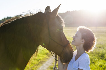 Profile von junger Frau und Pferd im Gegenlicht - TCF05424