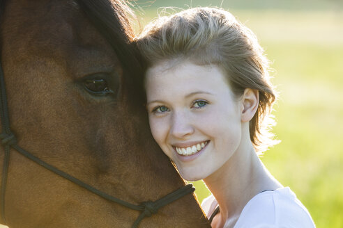 Porträt einer glücklichen jungen Frau mit Pferd - TCF05425