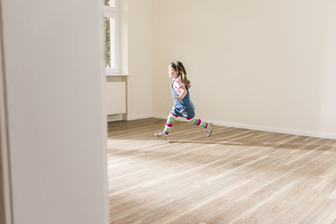 Happy girl running in empty apartment stock photo