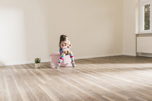 Girl in empty apartment holding teddy - UUF10763