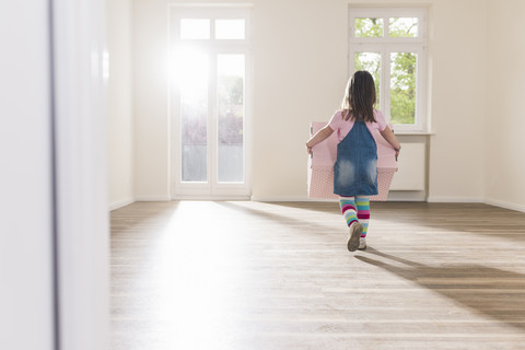 Girl carrying cardboard box in empty apartment stock photo