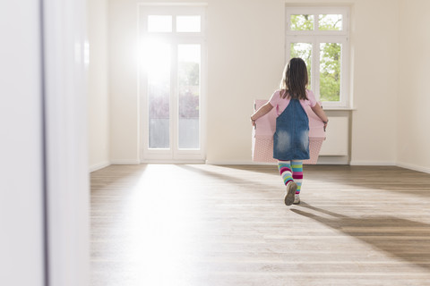 Mädchen mit Pappkarton in leerer Wohnung, lizenzfreies Stockfoto