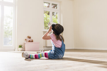 Mädchen in leerer Wohnung mit VR-Brille - UUF10765