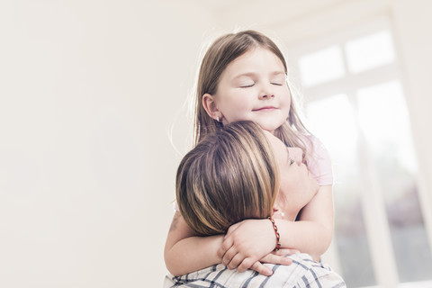 Mutter und Tochter umarmen sich in einer leeren Wohnung, lizenzfreies Stockfoto