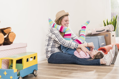 Glückliche Mutter und Tochter spielen im neuen Haus, lizenzfreies Stockfoto