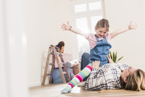 Happy mother and daughter playing in new home stock photo