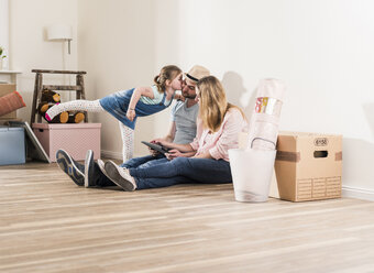 Parents and daughter using tablet in new home - UUF10782