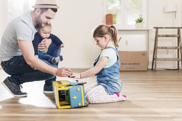 Father playing with two children in new home - UUF10791