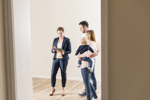 Immobilienmakler und Familie in neuer Wohnung - UUF10792