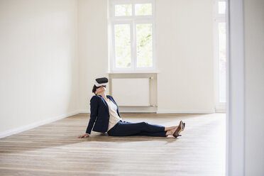 Frau in leerer Wohnung mit VR-Brille - UUF10801