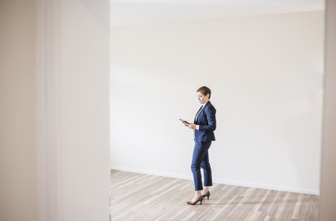 Frau in leerer Wohnung mit Tablet, lizenzfreies Stockfoto