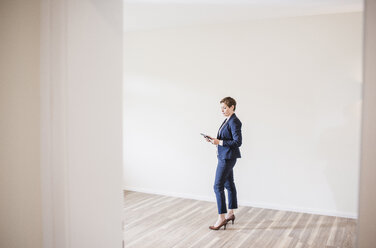 Woman in empty apartment with tablet - UUF10802