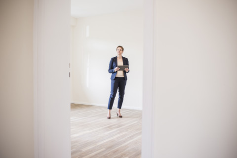 Woman in empty apartment with tablet stock photo