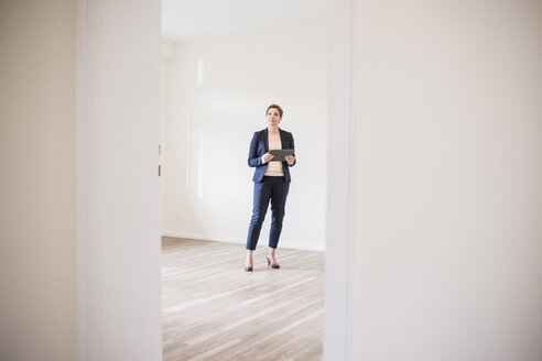 Woman in empty apartment with tablet - UUF10803