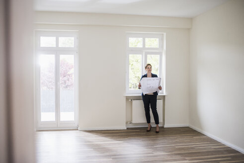 Woman in empty apartment with plan - UUF10804