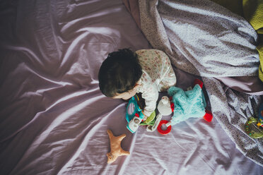 Baby-Mädchen spielt mit Spielzeug im Bett des Partners - GEMF01652