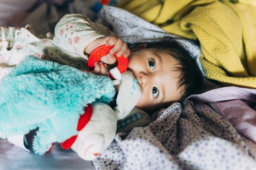 Baby-Mädchen spielt mit Spielzeug im Bett des Partners - GEMF01655