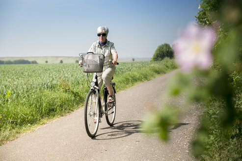 Germany, Senior woman riding bicycle in summer - FRF00515