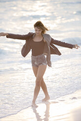 Junge Frau genießt den Strand bei Sonnenuntergang - ZOCF00417