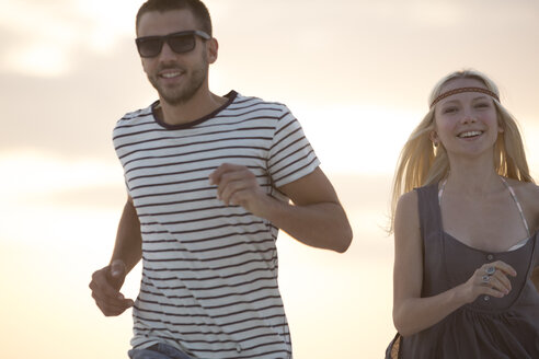 Young couple running on the beach - ZOCF00422