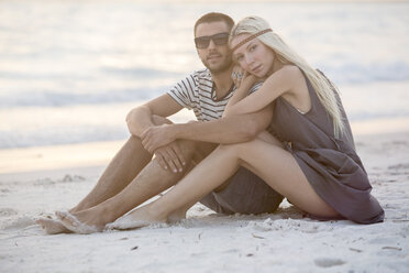 Young couple sitting on the beach, embracing - ZOCF00423