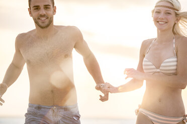 Junges Paar läuft am Strand und hält sich an den Händen - ZOCF00426