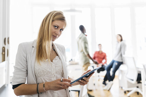 Young woman using digital tablet, looking at camera - JRFF01342