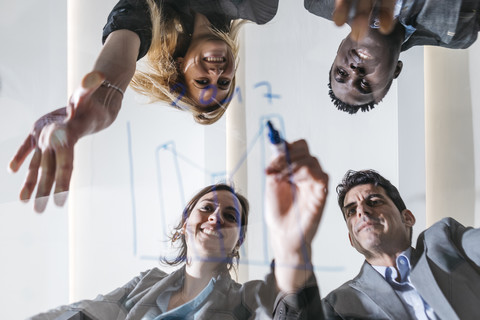 Geschäftsleute zeichnen Diagramm auf Glasscheibe, lizenzfreies Stockfoto