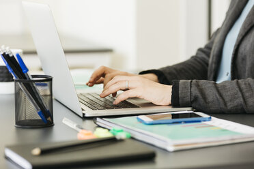 Businesswoman working in office, using laptop - JRFF01398