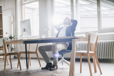 Geschäftsmann sitzt entspannt in einem modernen Büro - JOSF01001