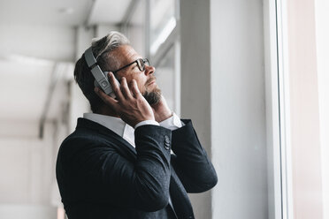 Businessman wearing head phones , listening music - JOSF01013