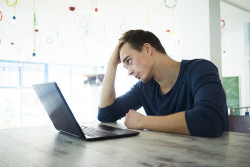 Junger Mann mit Laptop in einem Kaffeehaus - JOSF01035