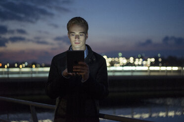 Portrait of young man using tablet outdoors at twilight - JOSF01046