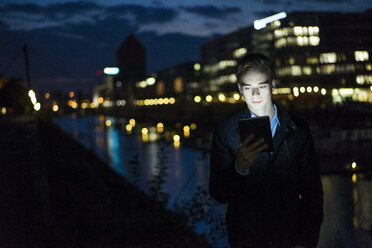 Young man using tablet outdoors at night - JOSF01049