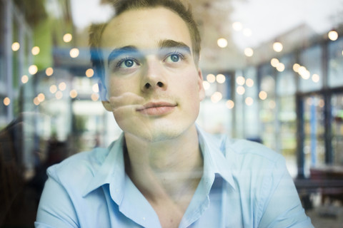 Daydreaming young man behind windowpane stock photo