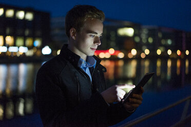 Young man using tablet outdoors at night - JOSF01055