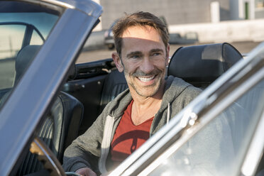 Portrait of smiling mature man sitting in his sports car - FMKF04160