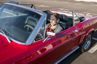 Mature man sitting in his red sports car - FMKF04161