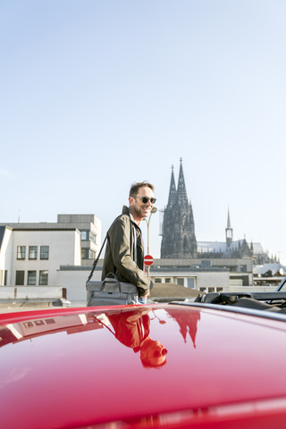 Germany, Cologne, portrait of smiling mature man with his parked sports car stock photo