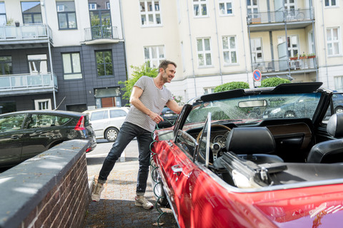 Lächelnder reifer Mann beim Waschen seines Sportwagens, lizenzfreies Stockfoto