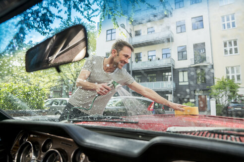 Smiling mature man washing his car - FMKF04172
