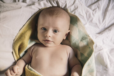 Porträt eines kleinen Jungen, der auf einem Bett liegt und in eine Decke eingewickelt ist - MFF03591