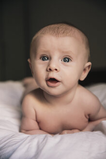 Porträt eines nackten kleinen Jungen auf dem Bett liegend - MFF03594