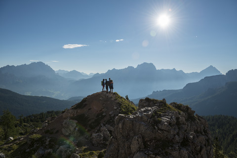 Italien, Freunde stehen auf einem Berggipfel in den Dolomiten und betrachten die Aussicht, lizenzfreies Stockfoto